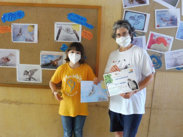 La niña Paz González muestra su dibujo y su diploma de ganadora de un primer premio, junto a Mónica de los Ríos, educadora ambiental de GREFA.